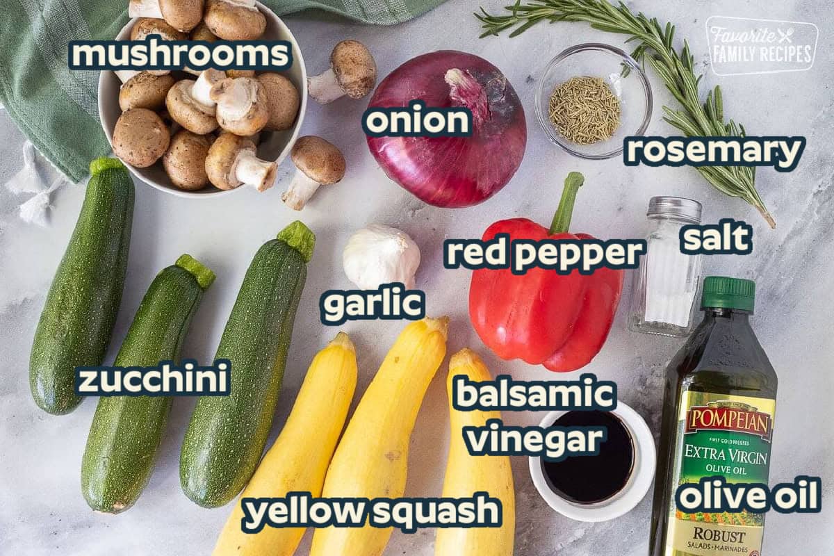 Ingredients to make Oven Roasted Vegetables including zucchini, yellow squash, red bell pepper, red onion, mushrooms, olive oil, balsamic vinegar, rosemary, garlic and salt.