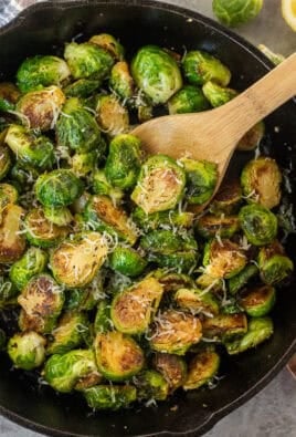 Skillet with Sautéed Brussels Sprouts with wooden spoon on top.