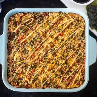 Sushi Bake in a casserole dish with soy sauce and nori on the side.