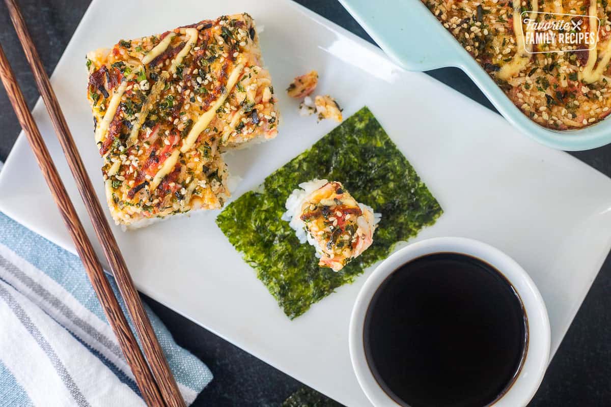 Sushi bake on top of a rectangle piece of nori. Bowl of sy sauce on the side.