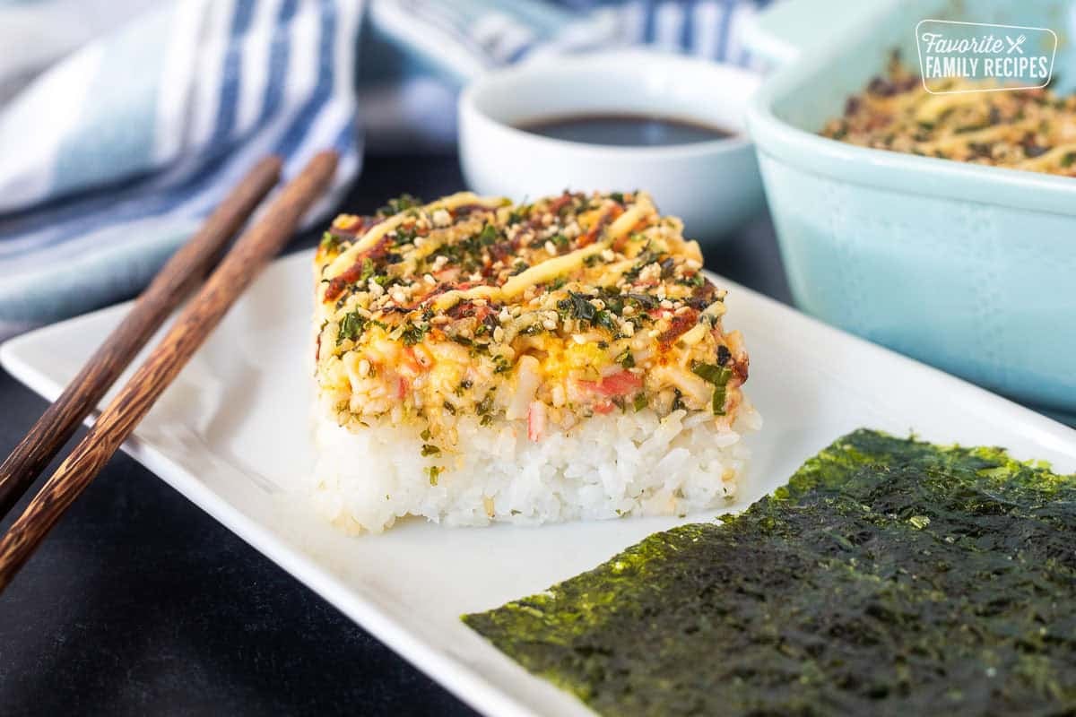 Sushi Bake slice on plate with Nori and chop sticks.
