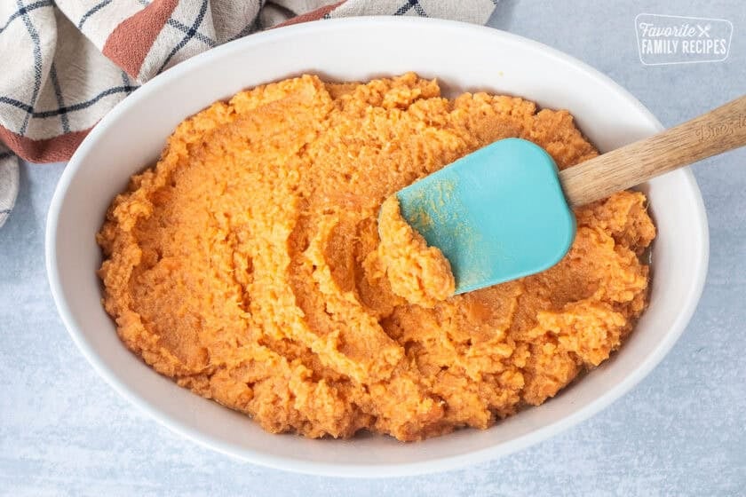 Baking dish with sweet potato mixture and a spatula.