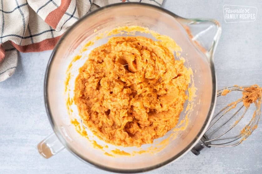 Glass mixing bowl with sweet potato mixture and whisk attachment.