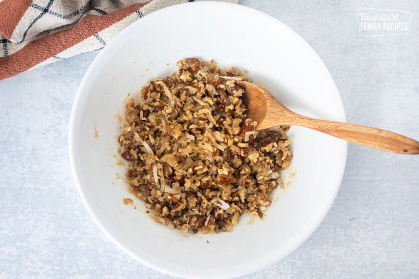 Glass bowl with pecan topping mixture and spoon.