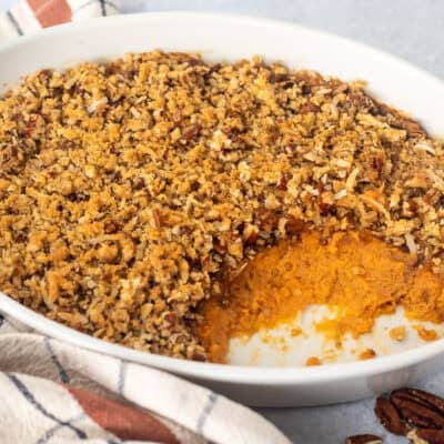 Sweet Potato Casserole with Pecan Topping in a baking dish with a portion missing.