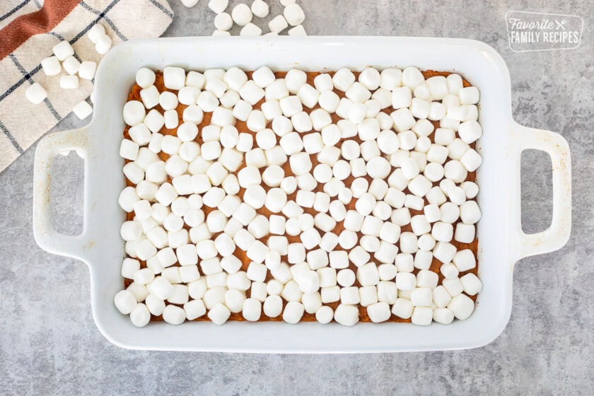 Marshmallows on top of sweet potatoes in a baking dish.