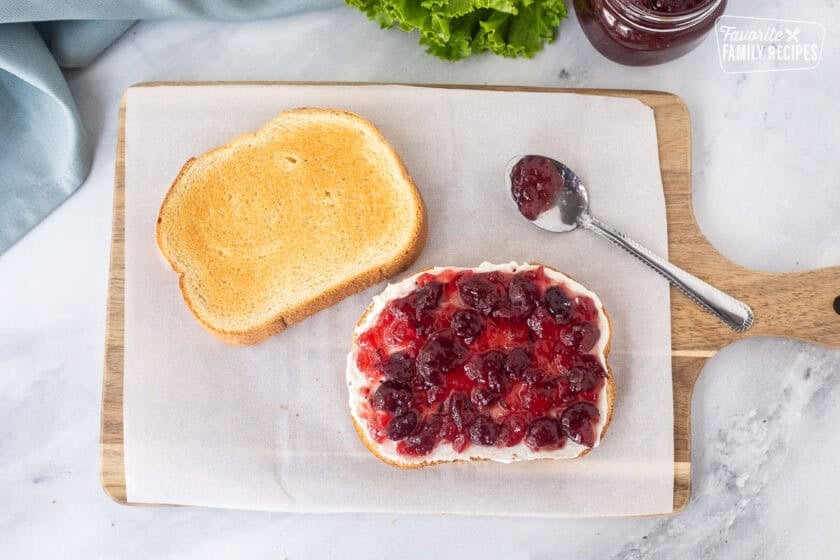 Cranberry sauce on top of cream cheese spread on one slice of toasted white bread.