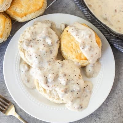 Plate with biscuits and gravy with cracked pepper on top.