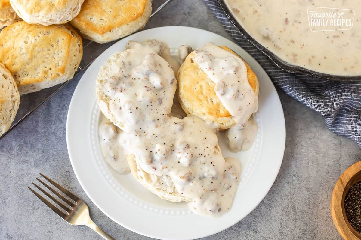 Plate with biscuits and gravy with cracked pepper on top.
