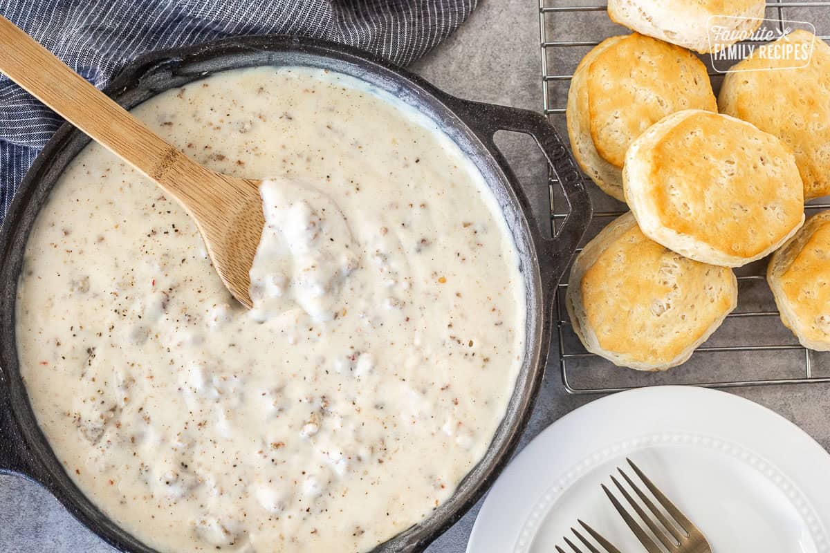 Sausage gravy in a skillet with biscuits on the side for a biscuits and gravy breakfast.