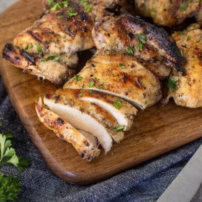 Sliced marinaded chicken thighs on a cutting board.