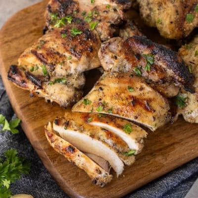 Marinaded chicken thighs sliced on a cutting board.