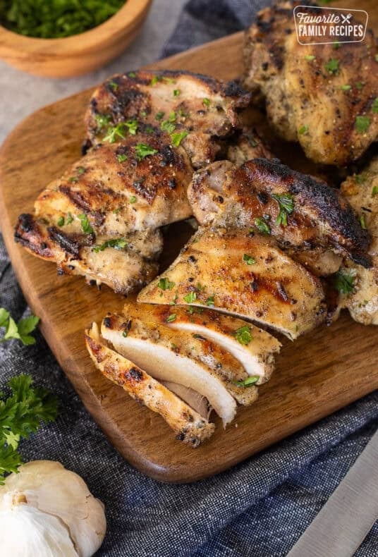 Marinaded chicken thighs sliced on a cutting board.