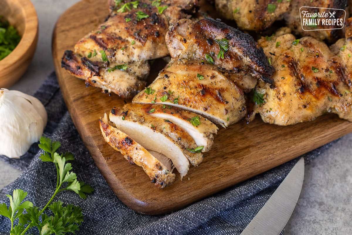 Sliced marinaded chicken thighs on a cutting board.