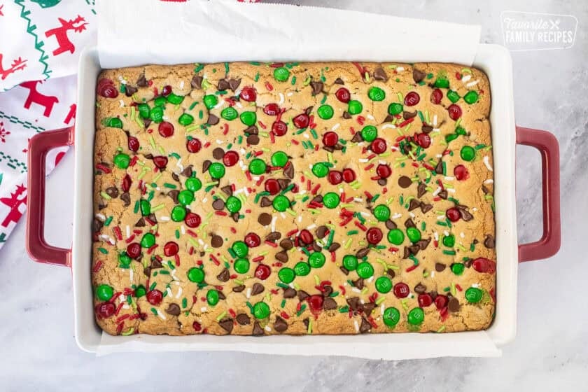 Baked Christmas cookie bars in a dish lined with parchment paper.