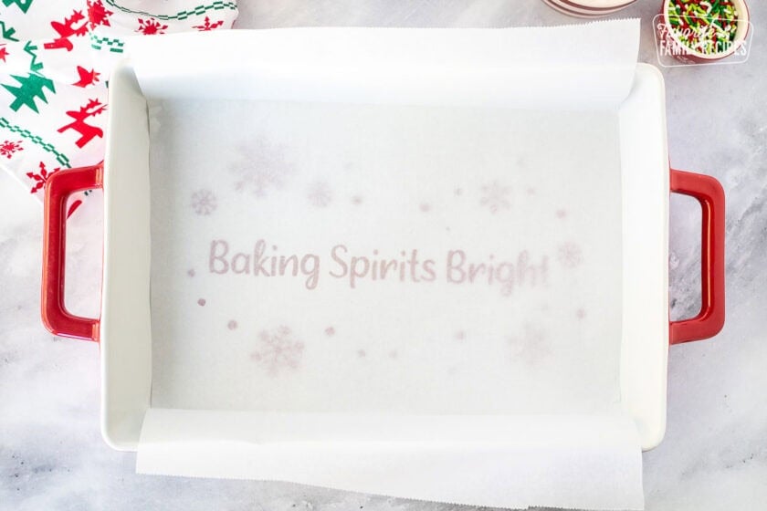 Baking dish lined with parchment paper that is long over the sides.