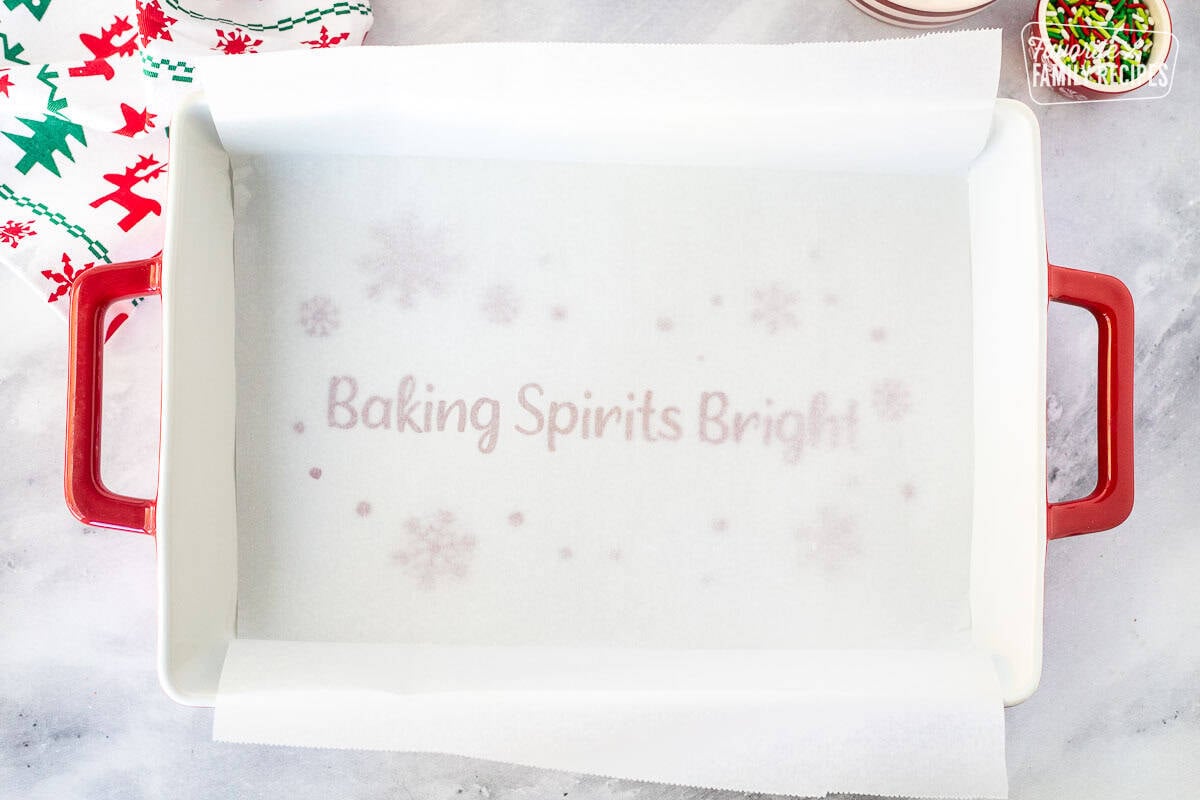 Baking dish lined with parchment paper that is long over the sides.