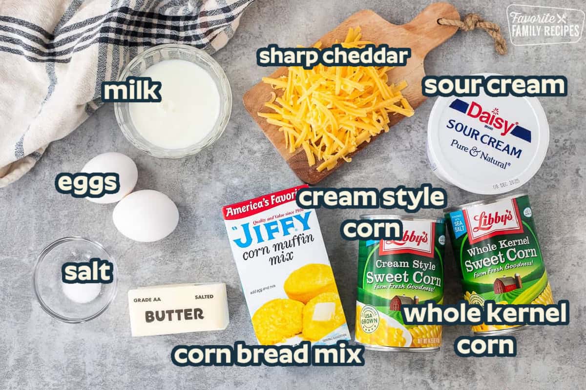 Ingredients to make cornbread pudding including cream style sweet corn, whole kernel sweetcorn, sour cream, sharp cheddar cheese, corn muffin mix, butter, eggs, milk and salt.