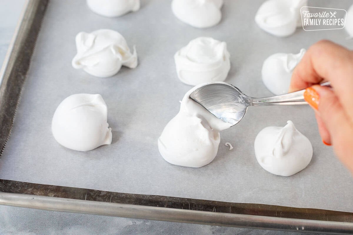 Dropping divinity onto sheet pan lined with parchment paper.