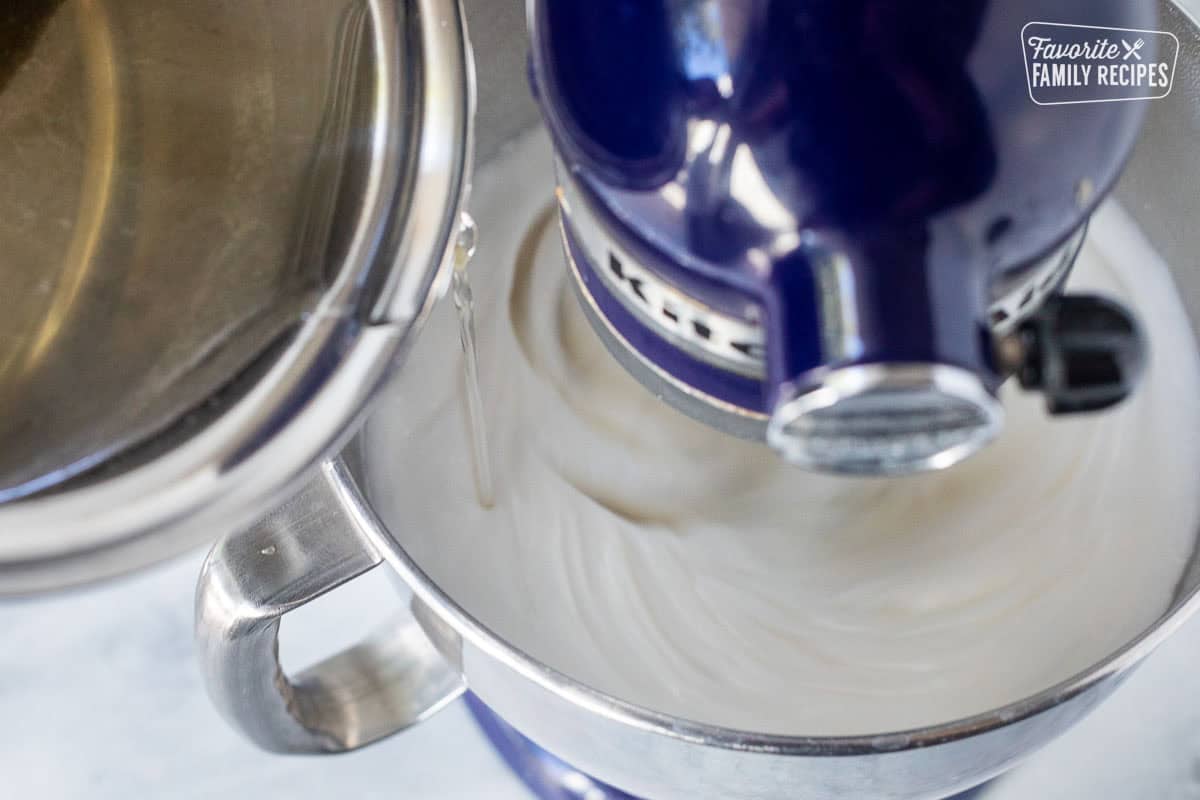 Slowly pouring hot candy mixture into egg whites while using stand mixer.