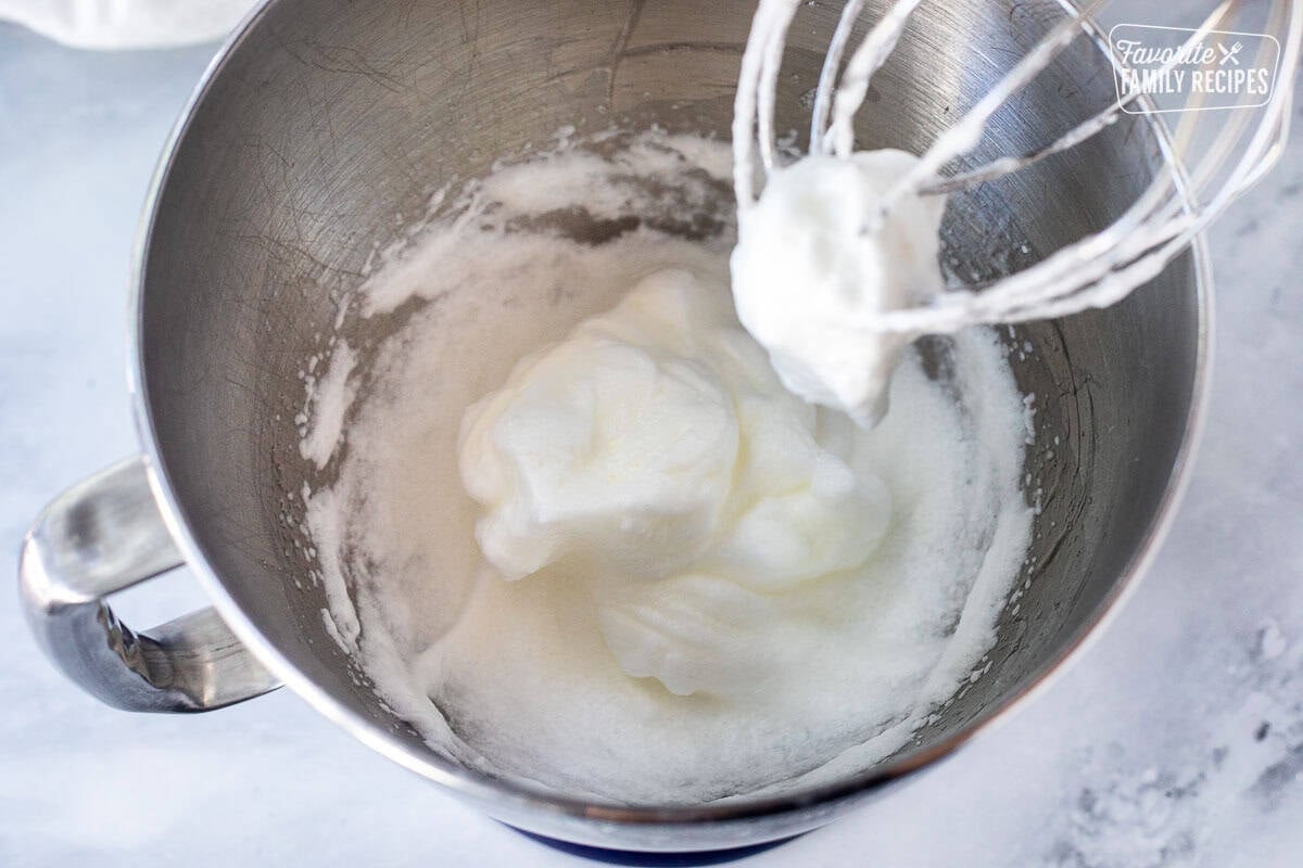 Whipped egg whites in a stand mixer bowl.