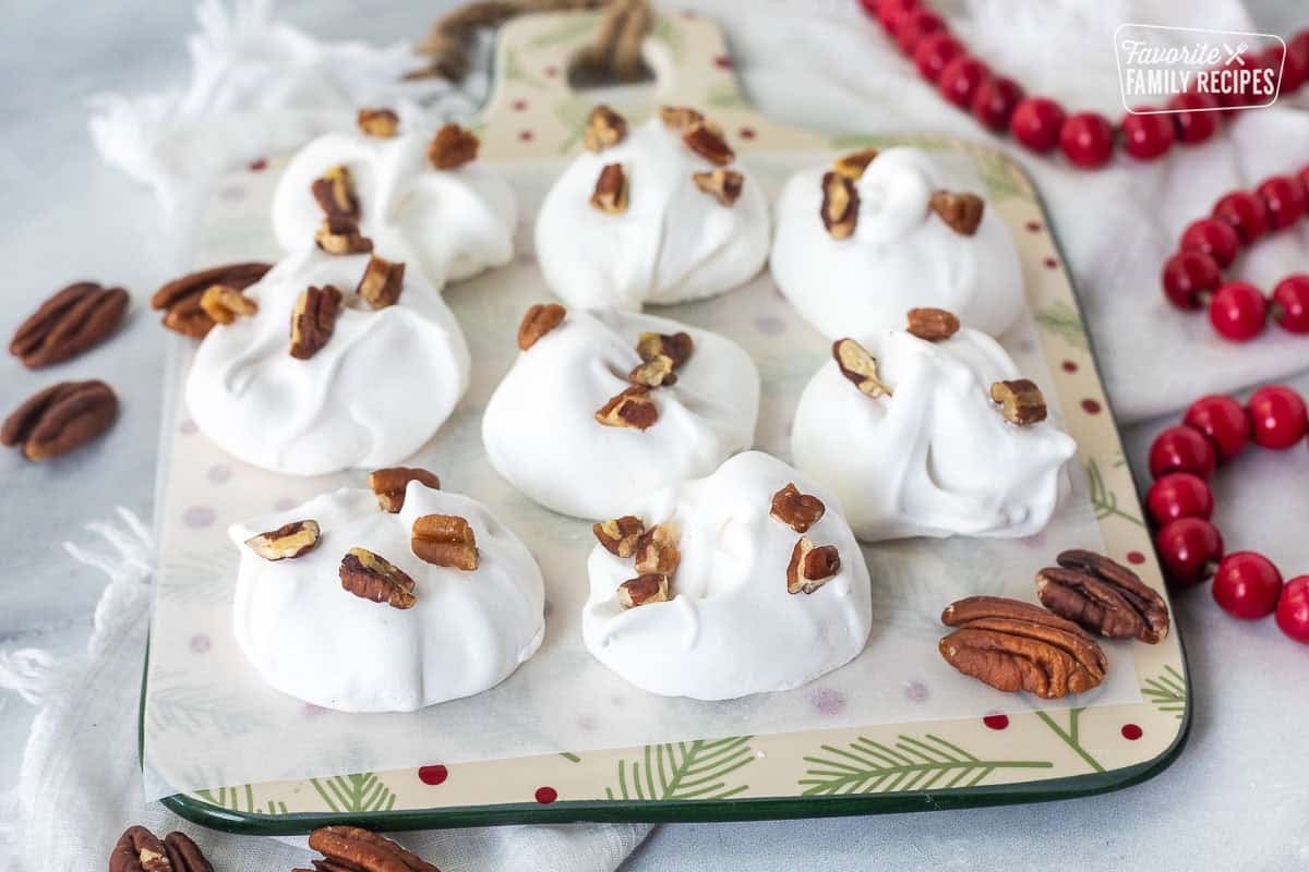 Divinity candy topped with chopped pecans on a dish lined with parchment paper.