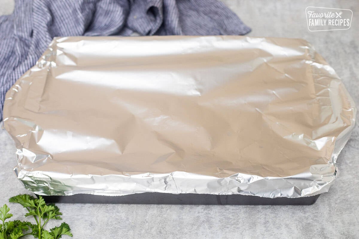 Covering chicken casserole baking dish with aluminum foil.