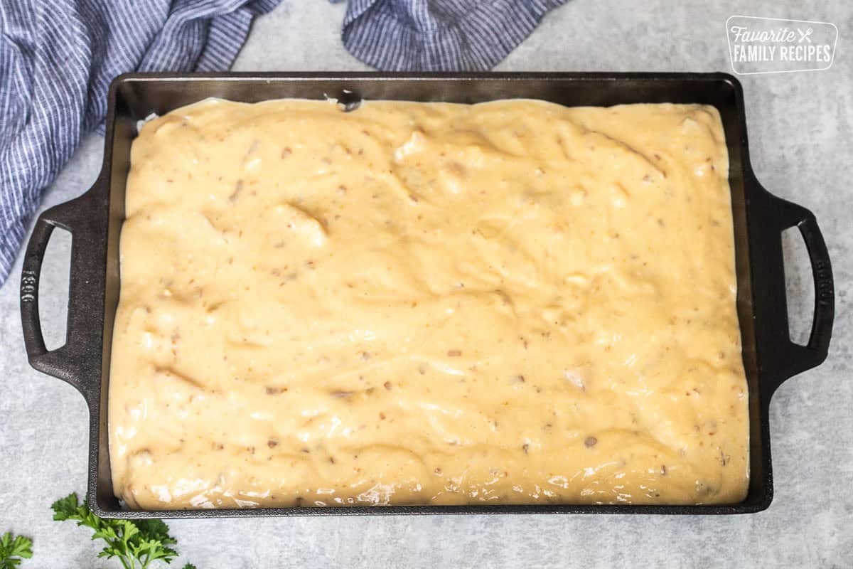 Baking dish with soup mixture on top of chicken pieces, rice and bottom soup mixture.