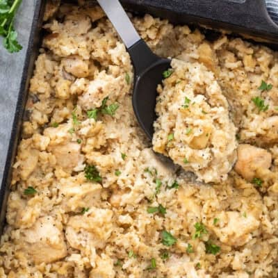 Spoon resting in baking dish of easy chicken casserole.