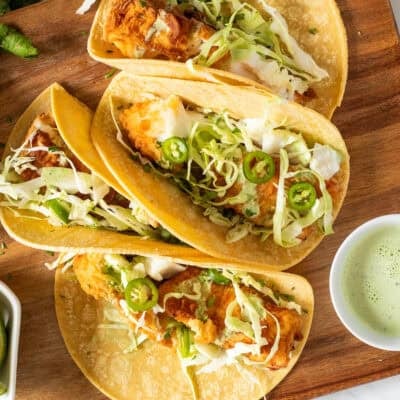 Four Halibut tacos with fried pieces of halibut, cabbage, green sauce and jalapeño.