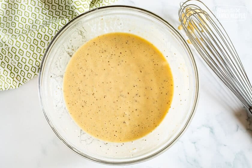 Glass bowl with mixed batter and whisk on the side.