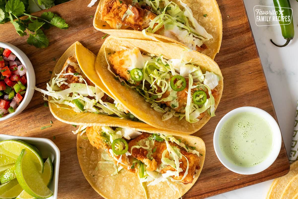 Four Halibut tacos with fried pieces of halibut, cabbage, green sauce and jalapeño.