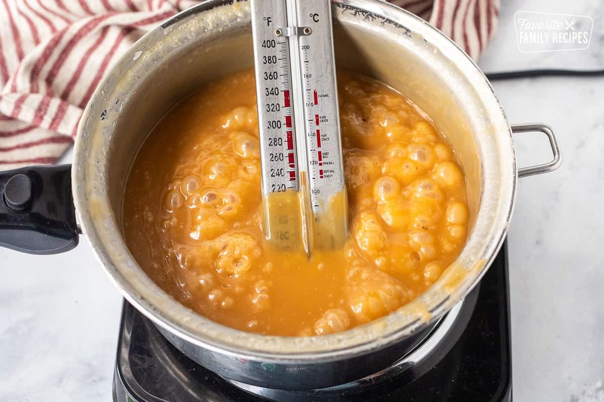 Boiled homemade caramel in a heavy saucepan with a candy thermometer.