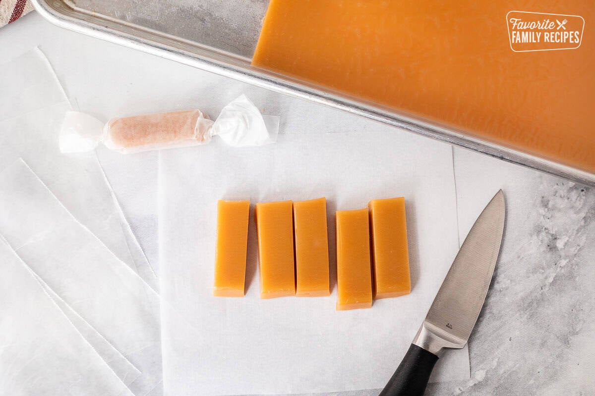 Cut pieces of Mom's homemade caramels on parchment paper with a knife.