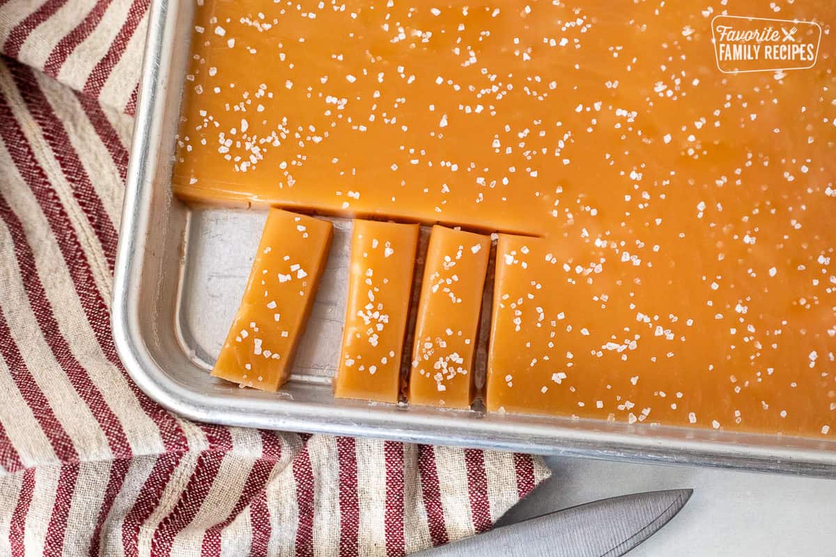 Pan of cut salted homemade caramels an knife on the side.