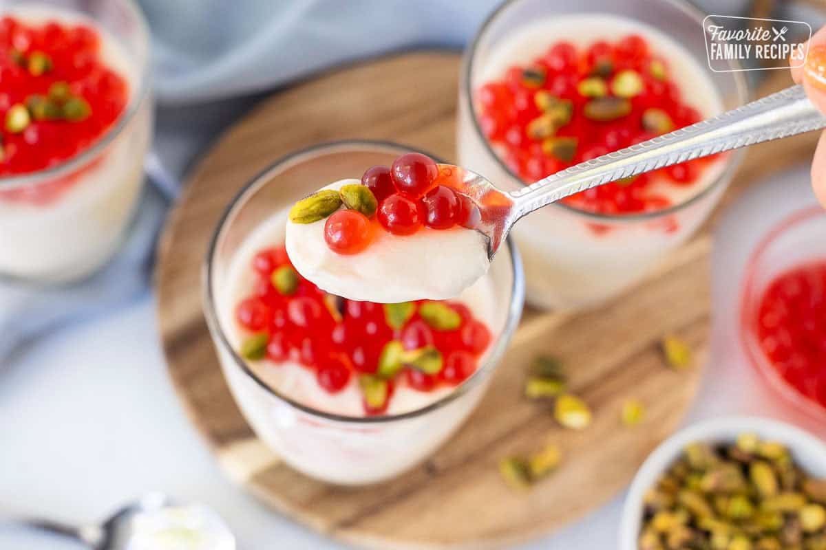 Spoon of Panna Cotta with strawberry bubbles and pistachios.