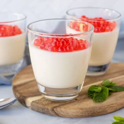 Three glasses of panna cotta topped with strawberry bursting bubbles.