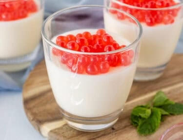 Three glasses of panna cotta topped with strawberry bursting bubbles.