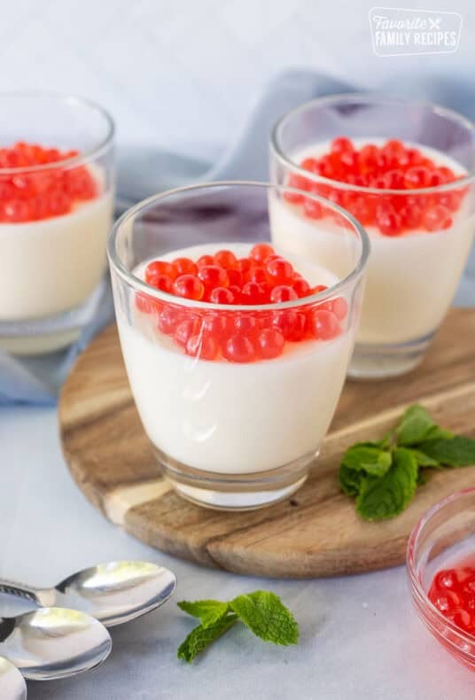 Three glasses of panna cotta topped with strawberry bursting bubbles.