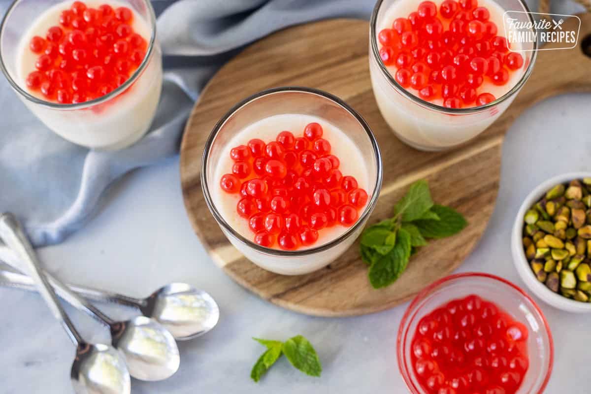 Three glasses of panna cotta topped with strawberry bursting bubbles.