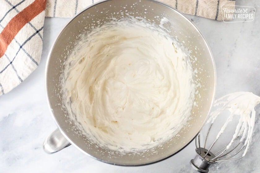Mixing bowl with whipped cream and whisk attachment on the side.