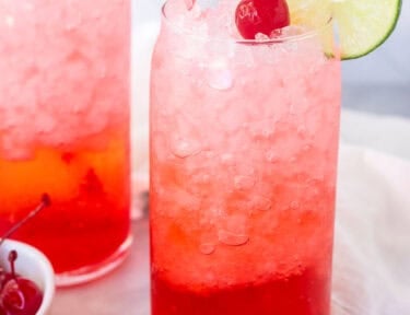Glasses of Shirley Temple Drinks garnished with lime slices and cherries.