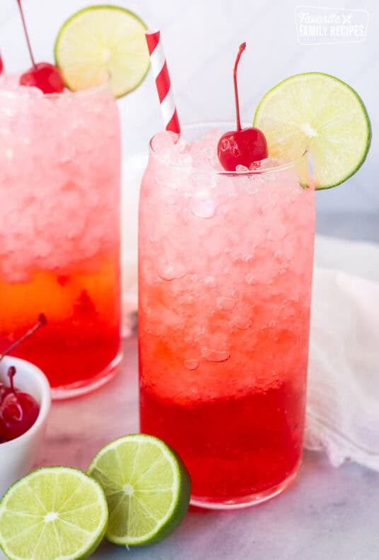 Glasses of Shirley Temple Drinks garnished with lime slices and cherries.