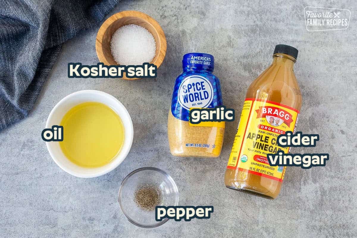 Ingredients to make chicken thigh marinade including apple cider vinegar, minced garlic, pepper, salt and canola oil.
