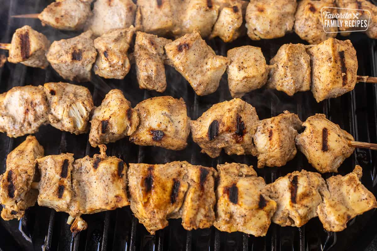 Chicken pieces on wooden skewers grilling over high heat to make chicken tikka masala