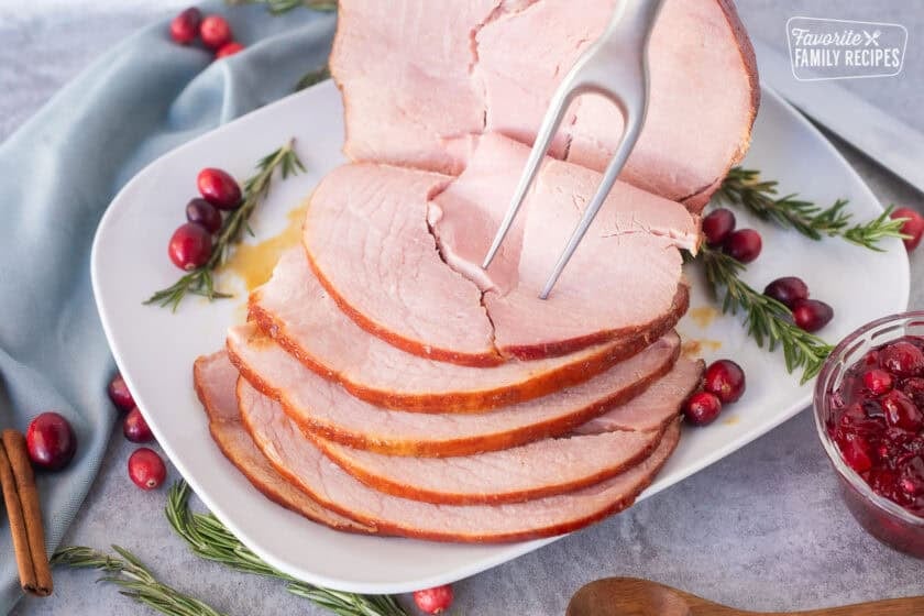 Serving fork piercing slice of Christmas ham.