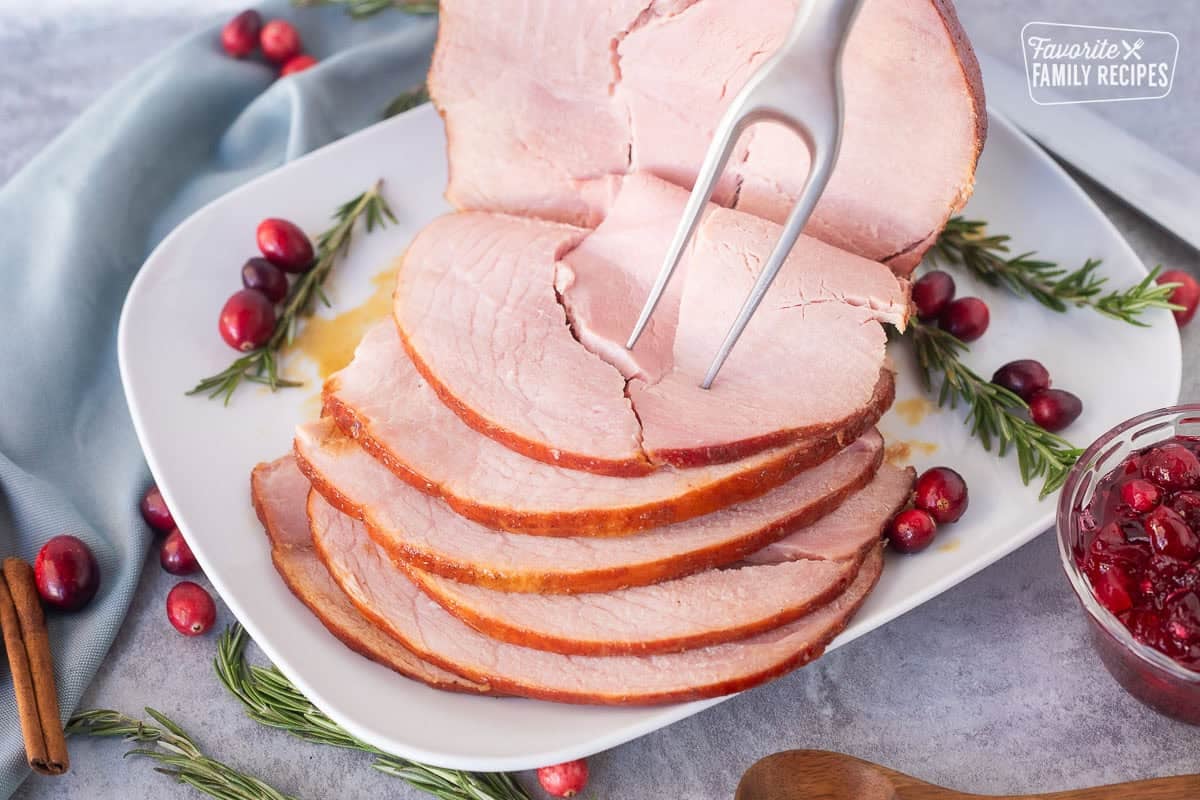Serving fork piercing slice of Christmas ham.