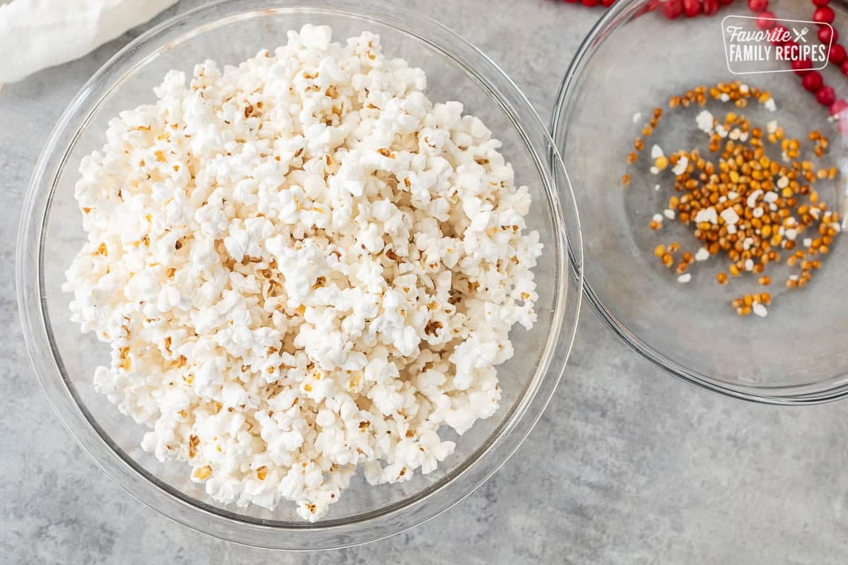 Bowl of popped popcorn next to a bowl of kernels.