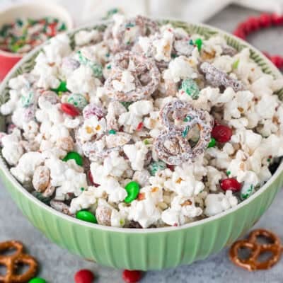 Bowl of Christmas popcorn with mini pretzels, red and green M&M's, roasted peanuts and festive sprinkles.