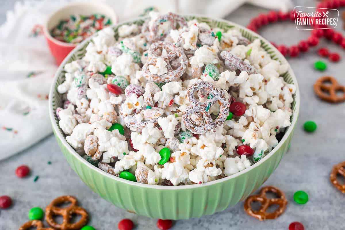 Bowl of Christmas popcorn with mini pretzels, red and green M&M's, roasted peanuts and festive sprinkles.